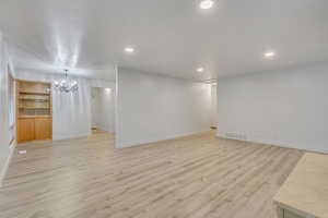 Unfurnished living room featuring light hardwood / wood-style flooring and a chandelier