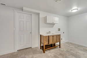 Clothes washing area featuring cabinets, hookup for a washing machine, sink, and electric dryer hookup