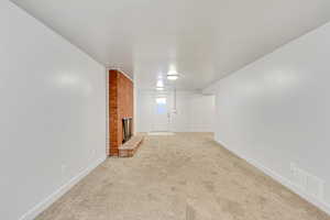 Unfurnished living room with light carpet and a fireplace