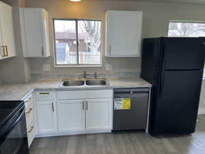 Kitchen with white cabinets, a sink, and black appliances