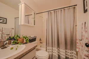 Full bathroom featuring vanity, toilet, and shower / bath combination with curtain