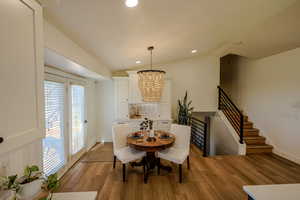 Dining room with lofted ceiling, light wood-type flooring, and an inviting chandelier