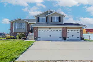 View of front of property featuring a garage and a front lawn