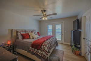 Bedroom with light hardwood / wood-style flooring, access to exterior, and ceiling fan