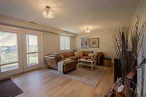 Living room with french doors, a notable chandelier, and light wood-type flooring