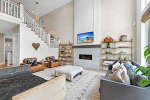 Living room with a towering ceiling, light hardwood / wood-style flooring, a chandelier, and a large fireplace