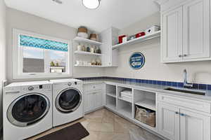 Laundry area featuring cabinets, sink, and washing machine and clothes dryer