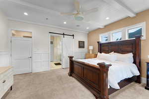 Bedroom featuring light carpet, beam ceiling, a barn door, and ceiling fan