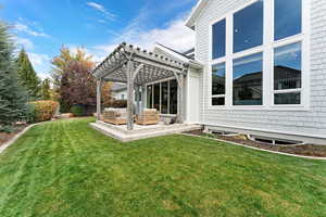 Back of property featuring a patio, a lawn, and a pergola