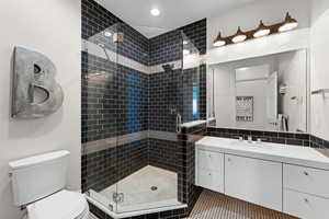 Bathroom with vanity, tile patterned floors, toilet, and an enclosed shower