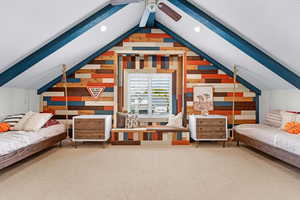 Additional living space with carpet, lofted ceiling with beams, ceiling fan, and wood walls