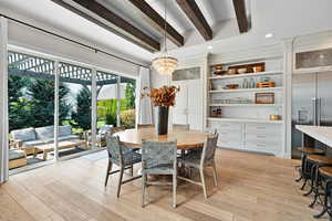 Dining area with light hardwood / wood-style flooring, a chandelier, and beamed ceiling