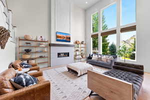 Living room featuring a large fireplace, a high ceiling, and light wood-type flooring