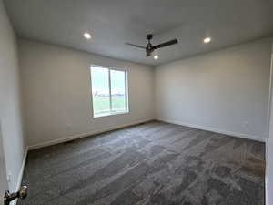 Spare room featuring ceiling fan and dark carpet