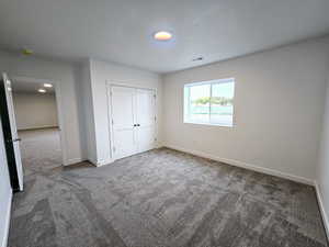 Unfurnished bedroom with a closet and dark colored carpet