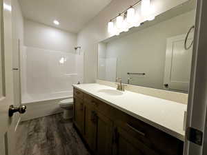 Full bathroom with vanity, toilet, shower / washtub combination, and hardwood / wood-style floors