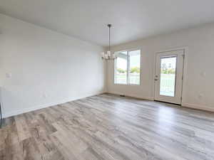 Empty room with light hardwood / wood-style floors and a chandelier