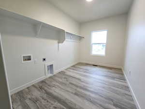 Laundry room with hookup for a washing machine, electric dryer hookup, and light hardwood / wood-style floors