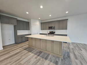 Kitchen featuring appliances with stainless steel finishes, a kitchen island with sink, light hardwood / wood-style flooring, gray cabinetry, and sink