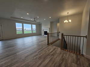 Living room featuring a raised ceiling, a textured ceiling, dark hardwood / wood-style flooring, and ceiling fan with notable chandelier