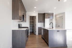 Kitchen featuring decorative backsplash, appliances with stainless steel finishes, dark hardwood / wood-style flooring, sink, and a center island with sink