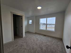 Carpeted empty room featuring a textured ceiling