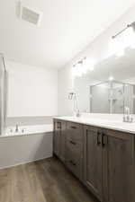 Bathroom featuring separate shower and tub, vanity, and hardwood / wood-style flooring