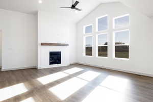 Unfurnished living room with wood-type flooring, high vaulted ceiling, and ceiling fan