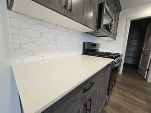 Kitchen featuring backsplash, stainless steel appliances, dark brown cabinetry, and dark hardwood / wood-style floors