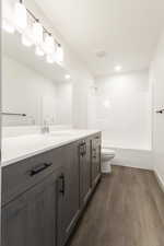 Full bathroom featuring washtub / shower combination, vanity, hardwood / wood-style flooring, and toilet