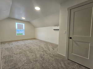 Bonus room featuring a wall unit AC, carpet flooring, and lofted ceiling