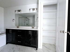 Bathroom with vanity, a shower with shower door, and a textured ceiling