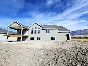 Back of property with a mountain view and a balcony