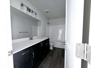 Full bathroom with toilet, hardwood / wood-style flooring, vanity, and shower / bathtub combination