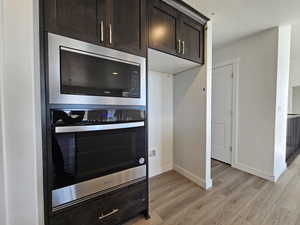 Kitchen featuring stainless steel appliances, light hardwood / wood-style floors, a textured ceiling, and dark brown cabinetry