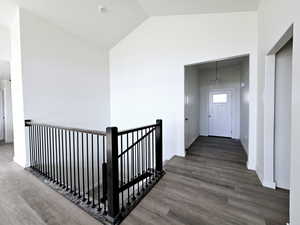 Corridor with an inviting chandelier, high vaulted ceiling, and dark wood-type flooring