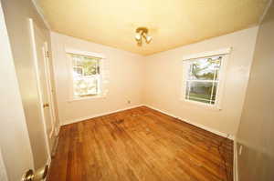 Empty room featuring a textured ceiling and hardwood / wood-style flooring