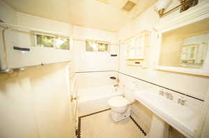 Bathroom with tiled shower / bath, toilet, and tile patterned flooring