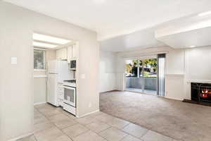 Kitchen featuring white appliances, light carpet, and white cabinetry