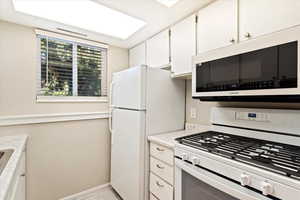 Kitchen featuring white appliances, white cabinetry, and light tile patterned floors