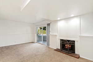 Unfurnished living room featuring a brick fireplace and carpet flooring