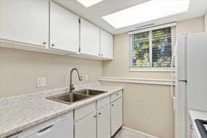 Kitchen featuring light tile patterned flooring, white cabinets, sink, and white appliances