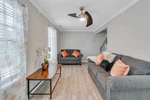 Living room featuring crown molding, wood-type flooring, and ceiling fan