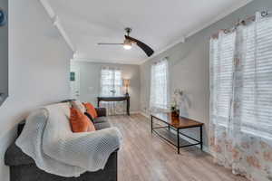 Living room with light hardwood / wood-style floors, ornamental molding, and ceiling fan