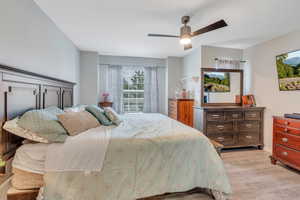 Bedroom with light hardwood / wood-style floors and ceiling fan