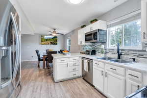 Kitchen featuring kitchen peninsula, ceiling fan, appliances with stainless steel finishes, white cabinetry, and sink