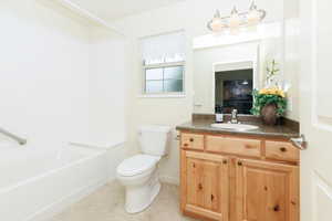 Full bathroom with vanity, toilet, shower / bath combination, tile patterned flooring, and baseboards