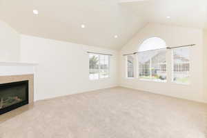 Unfurnished living room featuring carpet flooring, a tiled fireplace, high vaulted ceiling, recessed lighting, and baseboards