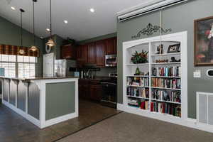 Kitchen featuring a kitchen breakfast bar, hanging light fixtures, stainless steel appliances, dark stone counters, and vaulted ceiling