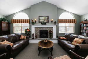 Living area featuring vaulted ceiling, a high end fireplace, and carpet floors